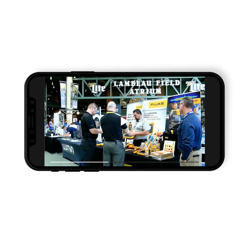 Screenshot on mobile phone showing video of people at trade show booth