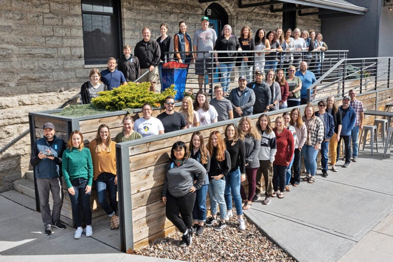 team photo of everyone standing in front of the Blue Door Consulting building