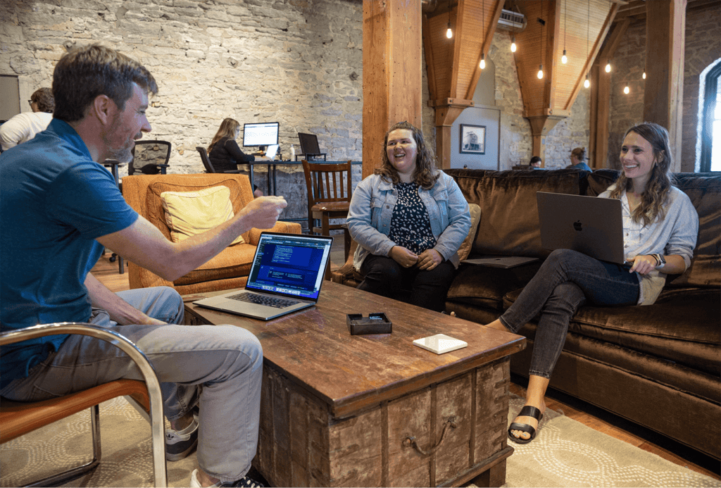 three Blue Doorians sitting around a table on couches with laptops