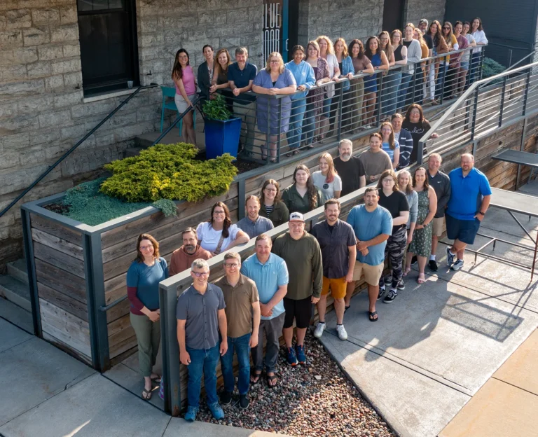 team photo of everyone standing in front of the Blue Door Consulting building